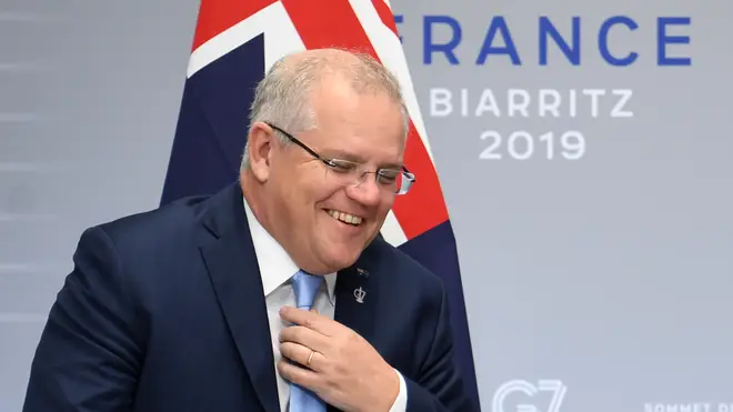Australian Prime Minister Scott Morrison adjust his tie and smiles