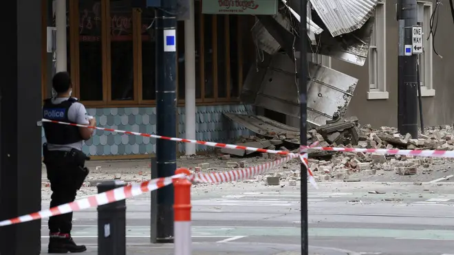 A police officer closes an intersection where debris is scattered in the road after an earthquake damaged a building in Melbourne