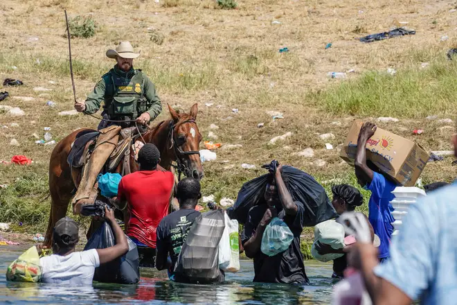 A United States Border Patrol agent on horseback uses the reins as he tries to stop Haitian migrants from entering an encampment on the banks of the Rio Grande