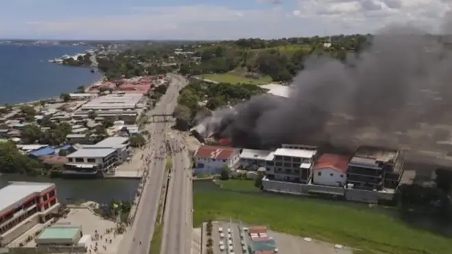smoke rises from burning buildings during a protest in Honiara