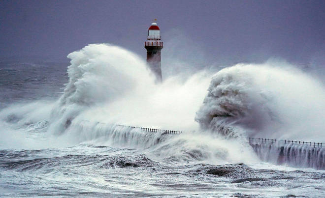 Huge waves crash the against the sea wall and Roker Lighthouse in Sunderland
