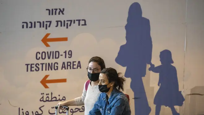 Travellers wearing face masks arrive at Ben Gurion Airport