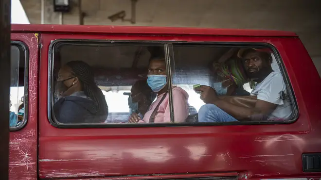 Passengers, some wearing masks, wait for their taxi to leave a taxi rank in Soweto in South Africa