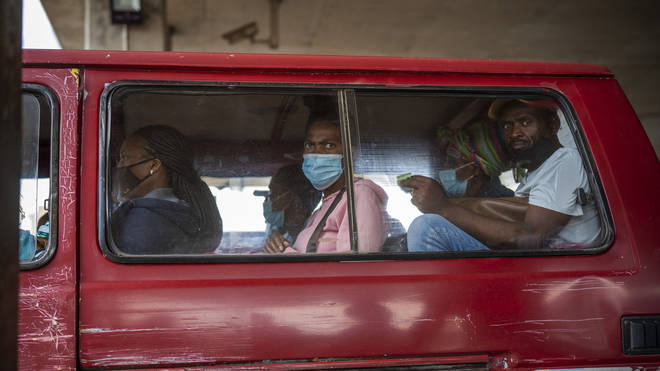 Passengers, some wearing masks, wait for their taxi to leave a taxi rank in Soweto in South Africa