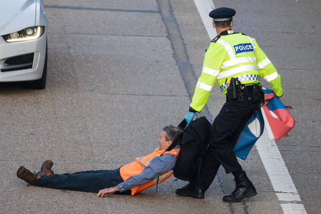 A Surrey Police officer drags an Insulate Britain climate activist on the M25 in September.