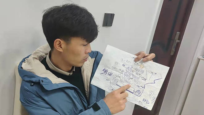 Li Jingwei points to a detailed map he drew from memory of his childhood village as he sits in Lankao in central China's Henan Province
