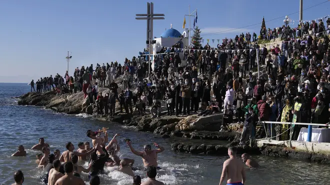 Pilgrims jump to catch the cross during a water blessing ceremony marking the Epiphany celebrations at Piraeus port, near Athens