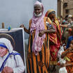 Homeless people gather beside a portrait of Saint Teresa