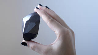 An employee of Sotheby’s Dubai presents a 555.55 carat black diamond