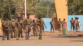 In this image made from video, mutinous Burkina Faso soldiers walk outside the Guillaume Ouedraogo military camp in Ouagadougou