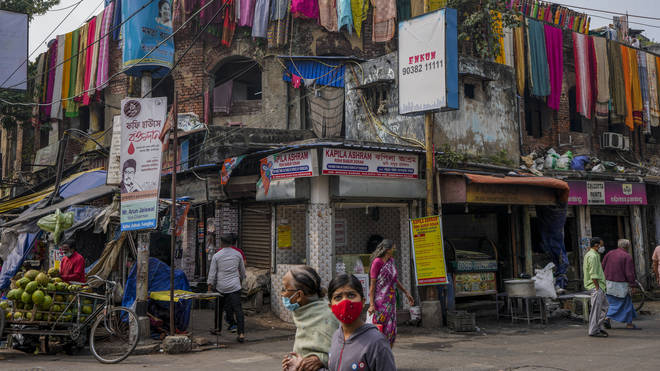 Commuters wearing masks walk past a cloth dyeing factory in Kolkata in India