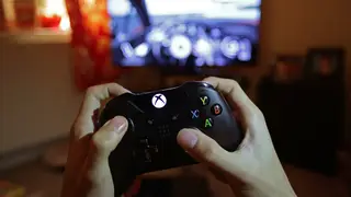 A teenager holding a controller to play the video game Forza Motorsport 5 on a Microsoft Xbox One console