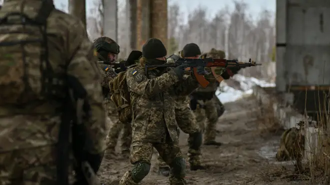 Ukrainian reservists aim rifles during training on the outskirts of Kyiv