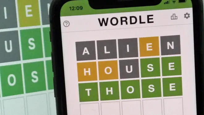 A mobile phone shows the screen of the popular online game Wordle