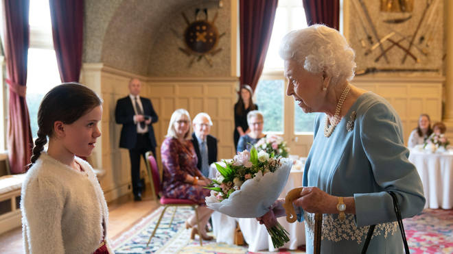 The Queen receives a posy from one of the young guests at the reception.