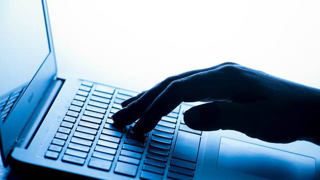 A woman’s hand presses a key of a laptop keyboard