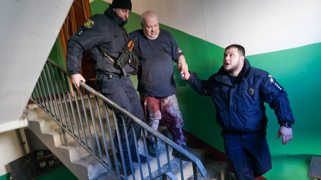 Ukrainian security forces accompany a wounded man after an airstrike hit an apartment complex in Chuhuiv, Kharkiv Oblast, Ukraine.