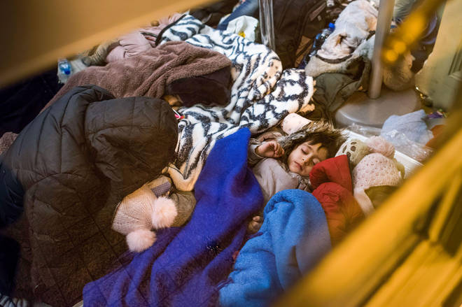 Refugee children are seen sleeping on the floor at a train station in Przemysl