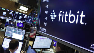 The logo for Fitbit appears above a trading post on the floor of the New York Stock Exchange
