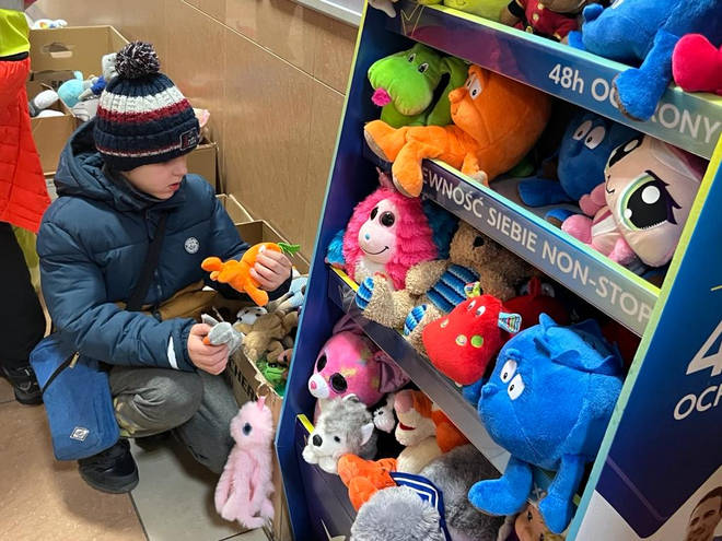 A young boy chooses a cuddly toy from a box of donations