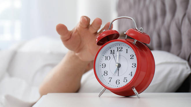 Hand turning off red alarm clock