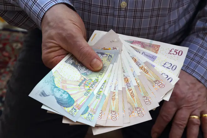 Person holds a fan of cash from £50 notes to £5