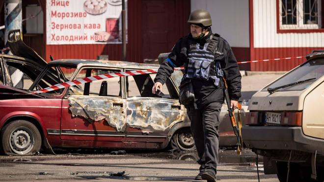 A Ukrainian police officer walks by calcinated cars outside a train station in Kramatorsk