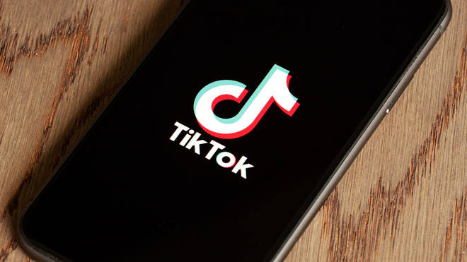 TikTok application icon on Apple iPhone 11 screen close-up. Tik Tok icon on smartphone with wooden backgroung. Tiktok Social media network from China