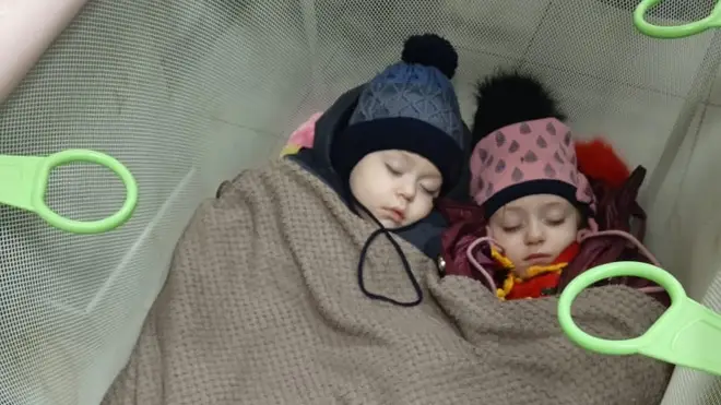 Miraslava, 5, and Danil, 2, asleep on a railway platform in Poland