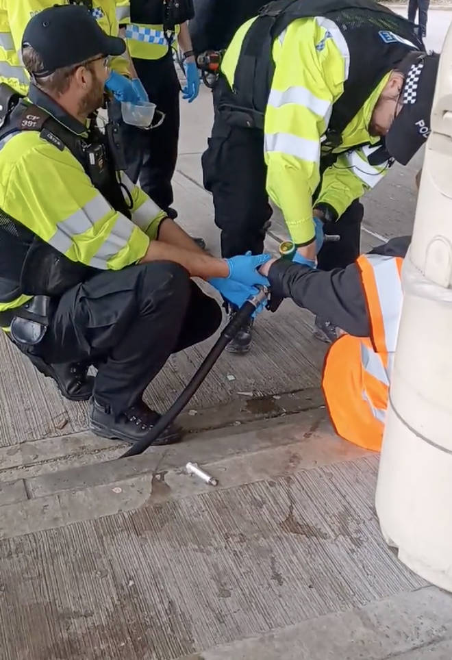 Police unstick a protester from a petrol pump