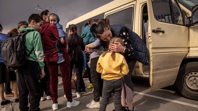 A woman kisses a girl after arriving at an evacuation point for people fleeing Mariupol