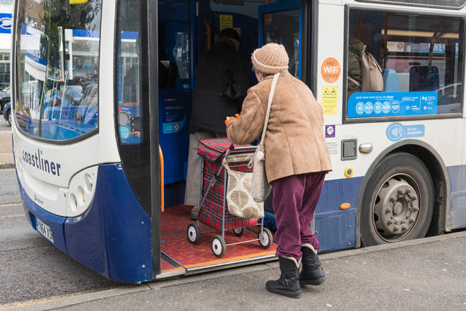 An elderly woman boards a bus (stock image).