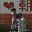 A couple wearing face masks walk by a wall displaying a words “I Love Chaoyang” as they heading to get tested for Covid-19 in the Chaoyang district in Beijing