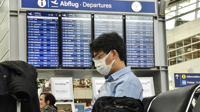 A passenger wearing a face mask waits for his flight at the airport in Duesseldorf, Germany