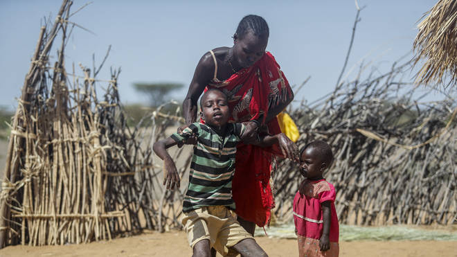 A mother helps her malnourished son stand after he collapsed near their hut in the village of Lomoputh in northern Kenya on Thursday May 12 2022