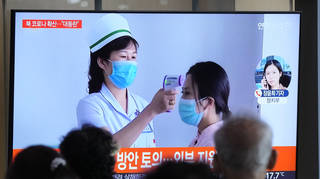 People watch a TV screen showing a news report about the COVID-19 outbreak in North Korea, at a train station in Seoul, South Korea, on Saturday