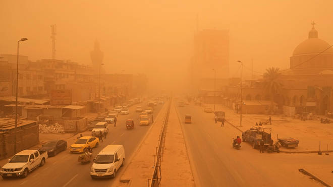 People navigate a street during a sandstorm in Baghdad, Iraq