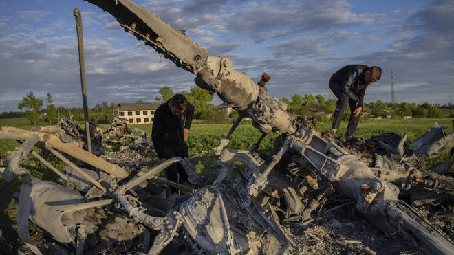 Oleksiy Polyakov, right, and Roman Voitko check the remains of a destroyed Russian helicopter lie in a field in the village of Malaya Rohan, Kharkiv region, Ukraine