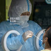 A worker wearing a protective suit administers a Covid-19 test at a coronavirus testing site in Beijing