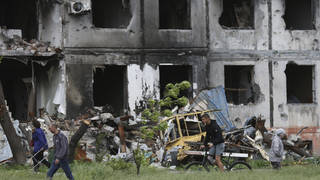People walk past a destroyed building in Mariupol