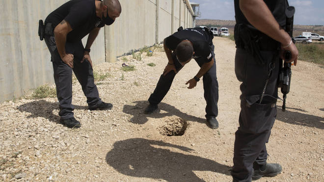 Police officers and prison guards inspect the scene of the escape
