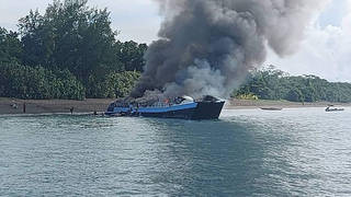 Smoke billows from the M/V Mercraft 2 ferry as it is towed to an island off the town of Real, Quezon province, Philippines