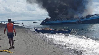 Smoke billows from ferry M/V Mercraft 2 as it is towed to an island off of the town of Real, Quezon province, Philippines, on Monday, May 23 2022