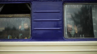 A child and a man, fleeing from heavy shelling, wave to a photographer before departing in an evacuation train at Pokrovsk train station