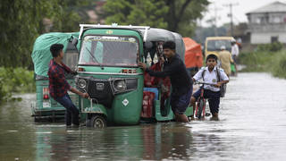 People push an auto rickshaw through a flooded road as a school boy rides his bicycle behind in the Bagha area in Sylhet, Bangladesh, on Monday May 23 2022