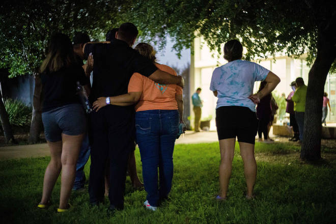 Families huddle and hug, awaiting news of missing relatives from carnage at their local elementary school.