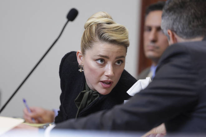 Amber Heard speaks to her attorney at the Fairfax County Circuit Courthouse in Fairfax, Virginia.