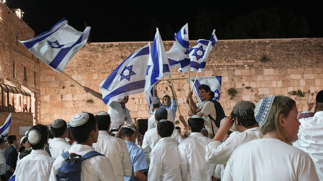 Young Jewish people wave Israeli flags near the Western Wall in Jerusalem