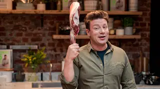 Jamie Oliver holds a piece of raw pig aloft