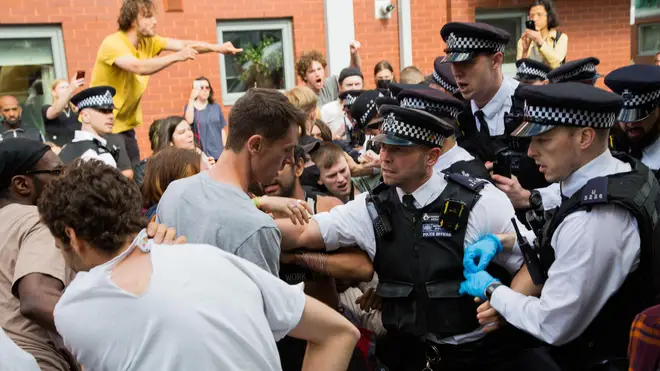 People clash with police during a Immigration raid at Evan Cook Close